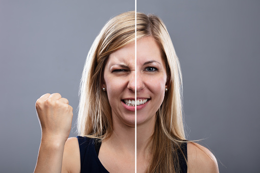 Close-up Of A Woman Showing Angry And Happy Expression On Grey Background
