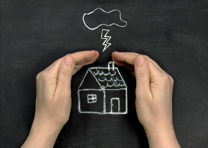 hands protect the house drawn in chalk on the Board from the storm